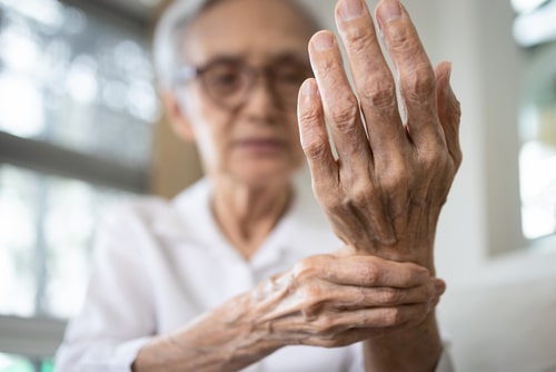 Elderly woman holding hand in pain