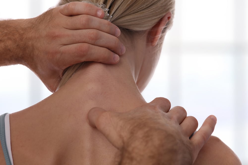 Osteopath treating female patient for neck pain